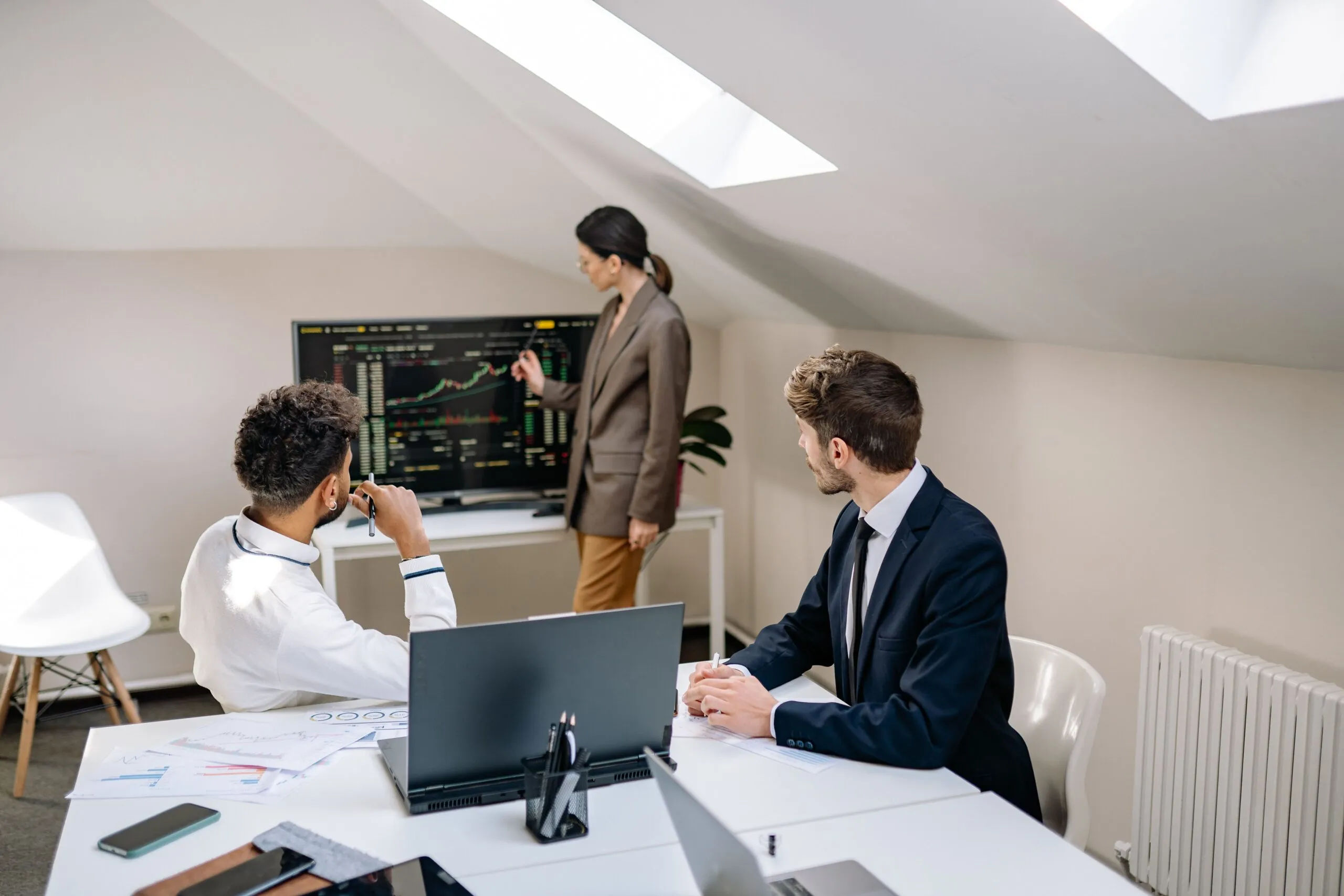 Professionals discussing stock market trends with charts in an office setting.