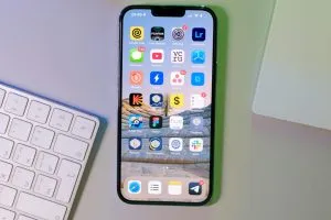 Smartphone on a desk with visible apps, keyboard, and headphones.