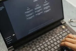 Close-up of hands typing on a laptop with AI software on the screen, highlighting modern technology use.