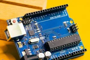 Close-up of an Arduino microcontroller on a vibrant yellow background, showcasing electronic innovation.