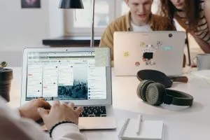Young team collaborating at a modern workspace with laptops and headphones.