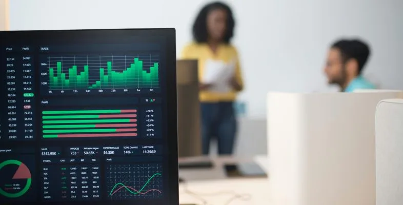 Modern office with financial trading screens and a diverse team discussing strategies.