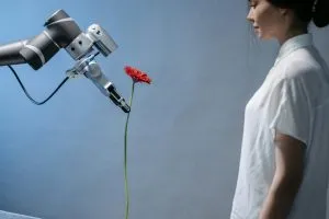 A woman observes a robot holding a red flower, symbolizing technology and nature integration.